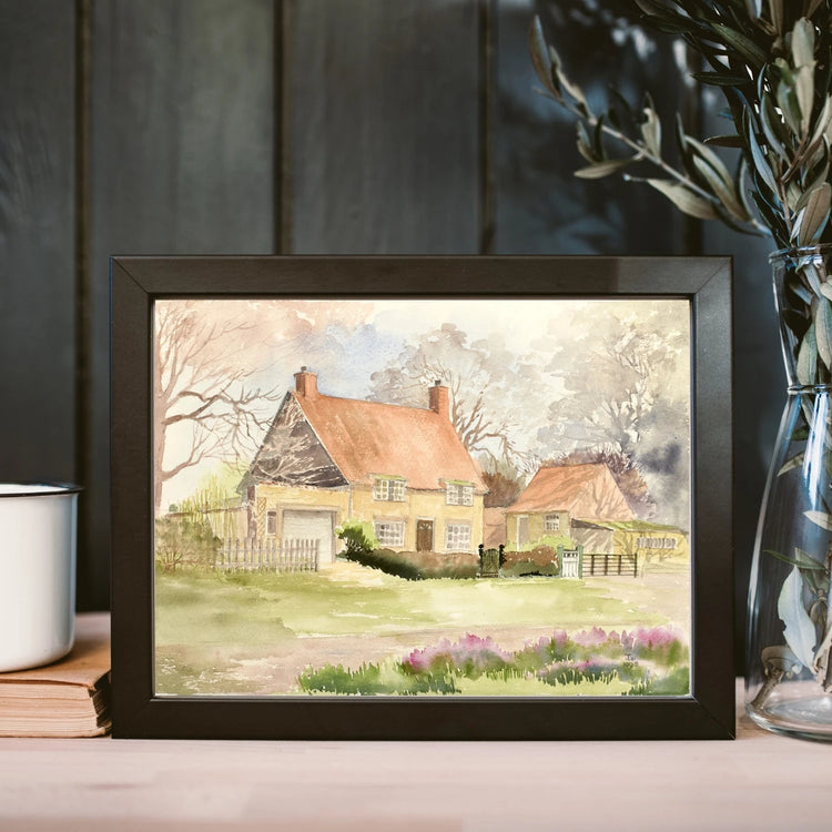 Black framed print of a Lincolshire house on a shelf next to a modern glass vase