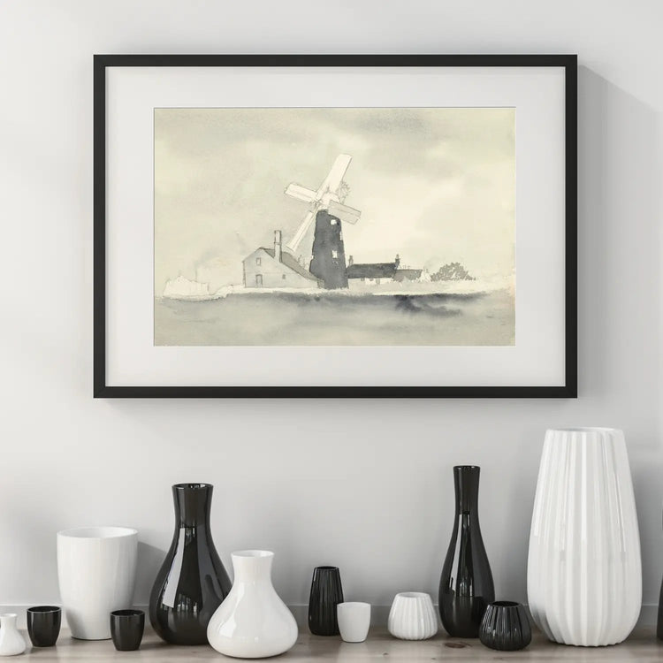 Framed and mounted windmill print on a white wall above assorted black and white vases