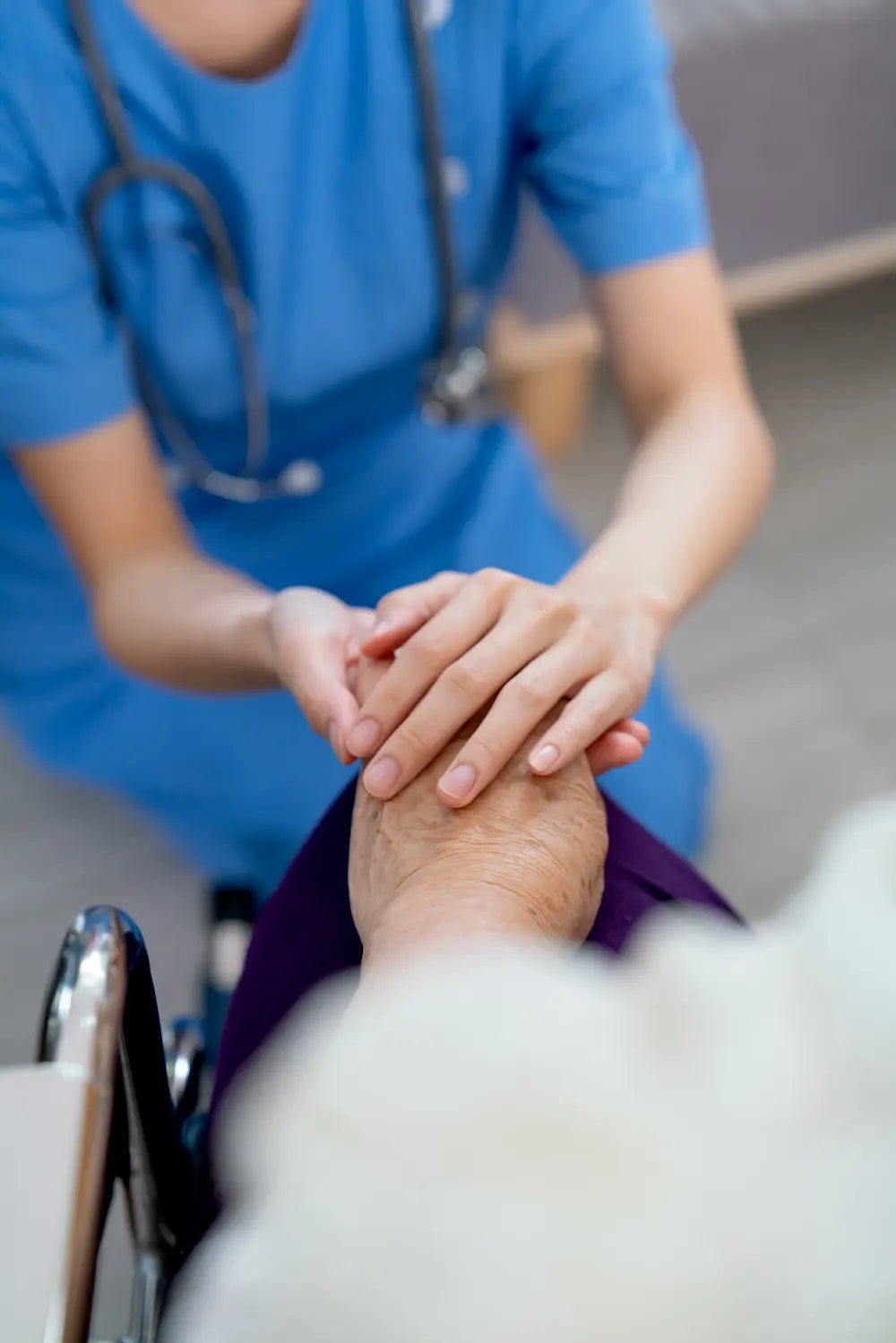 A doctor holding an elderly patients hand